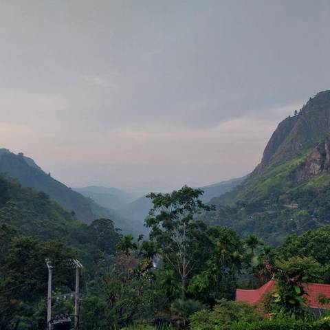 Scenic view of lush mountains and cloudy sky.