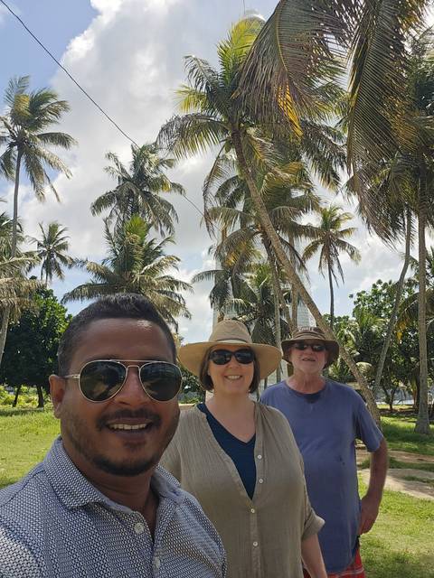 Group of three people under palm trees enjoying a sunny day.