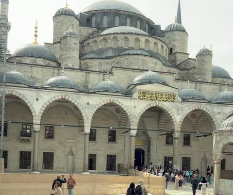       Exterior of a mosque with ornate domes and Arabic script.
  