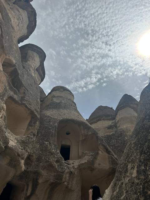       Rock formations with caves under a partly cloudy sky.
  
