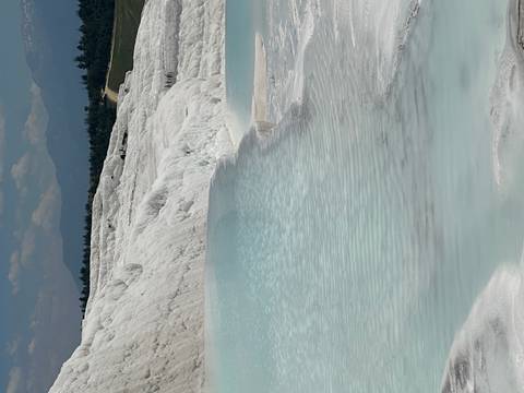       Travertine terraces with shallow pools of water.
  