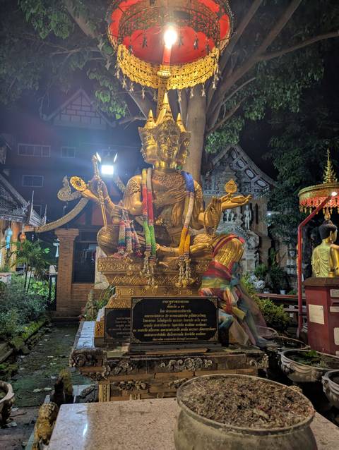 Golden statue of a deity in a temple at night.