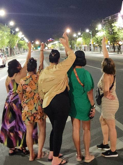 People walking at night, raising their arms.