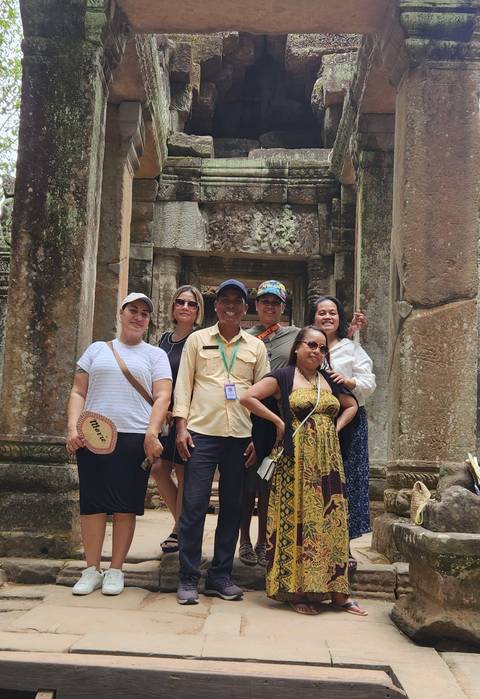 Group of people standing in front of an ancient stone structure.