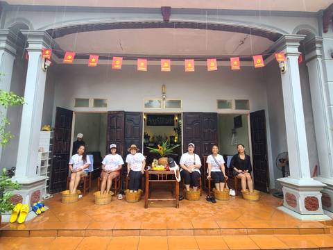       Women sitting with their feet in wooden buckets for a foot bath.
  