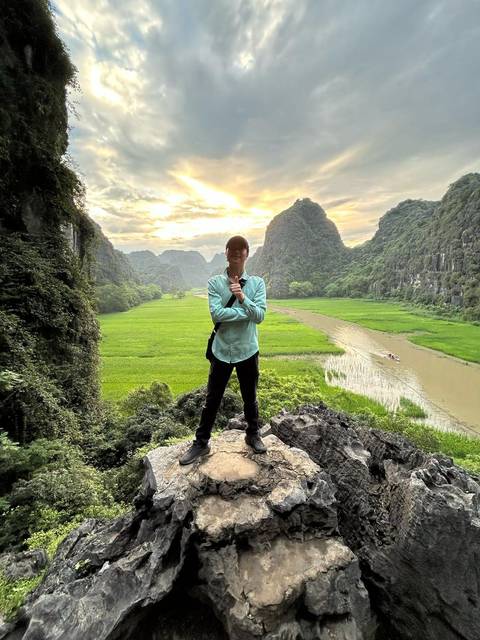       Man standing with scenic view of mountains and a river.
  