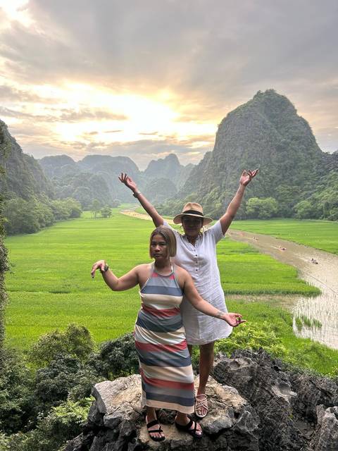 Two women posing in front of a scenic landscape with karst mountains.