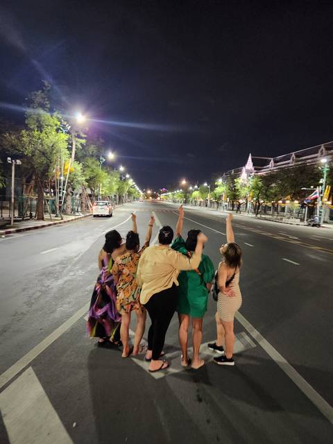 Group facing away on a deserted street at night.