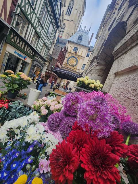 Colorful flower market with a historic clock in the background.