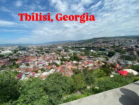 Panoramic view of Tbilisi with large overlay text.