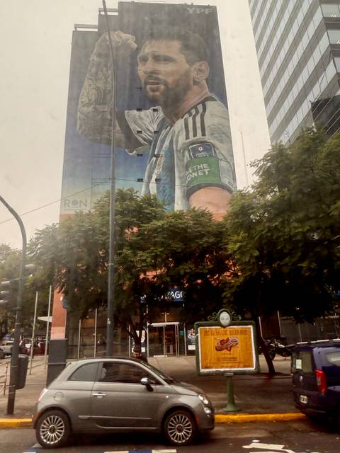       A large mural on a building viewed through trees.
  