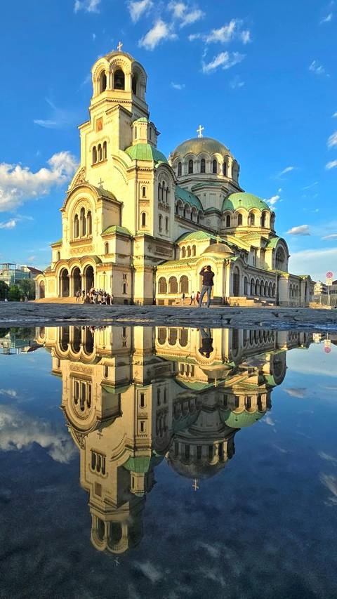       Historic building with reflection in a puddle.
  