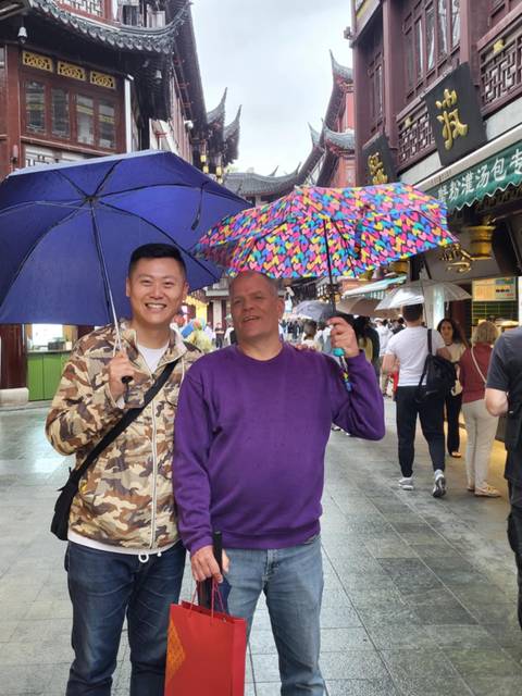 Two people under umbrellas in a busy street.