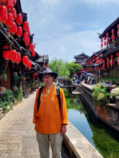 Person posing in a traditional street with red lanterns.
