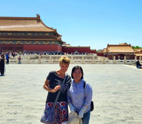 Two women posing in front of a historic Chinese building.