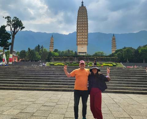       Two people posing in front of a tall pagoda.
  