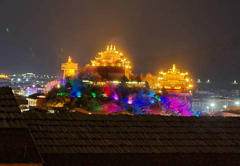 Illuminated traditional building at night with vibrant colors in the background.