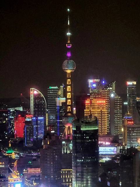       Cityscape at night featuring brightly lit modern architecture.
  