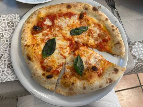 Margherita pizza with basil leaves on top.