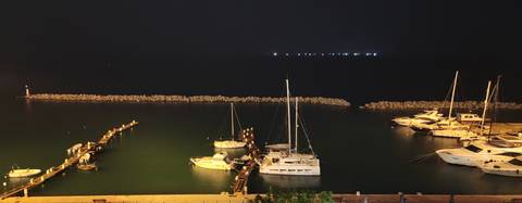       Docked boats at night with faint distant lights.
  