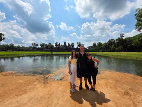 Smiling group posing with Angkor Wat temple in background.