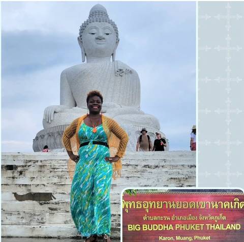 Person posing in front of a large Buddha statue.