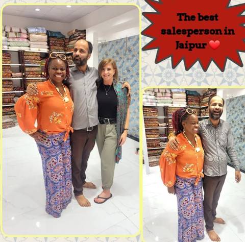       People posing with textiles inside a colorful shop.
  