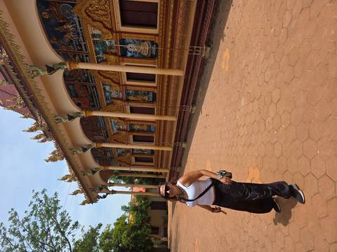 A person posing in front of a detailed temple with art and architecture.