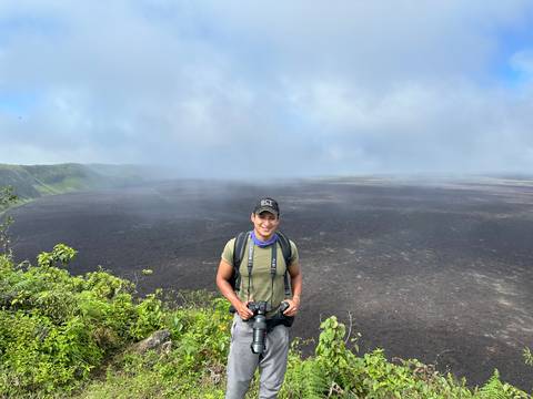       Person posing with a volcanic landscape in the background.
  