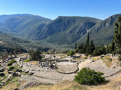 Ruins of an ancient amphitheater with mountainous backdrop.