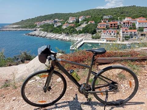       A bicycle parked overlooking a coastal residential area.
  
