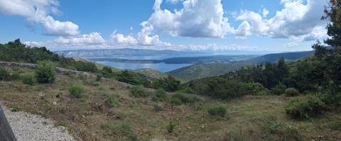       A panoramic view of a green landscape with mountains and a lake.
  