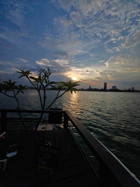 Sunset over a large river with a city skyline in the distance.