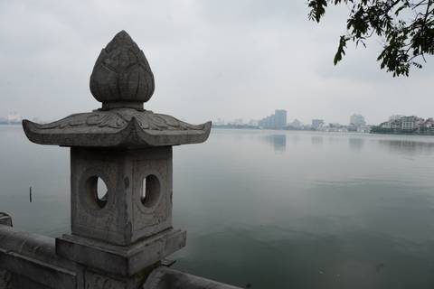 A pagoda overlooking a large calm lake with city buildings in the background.