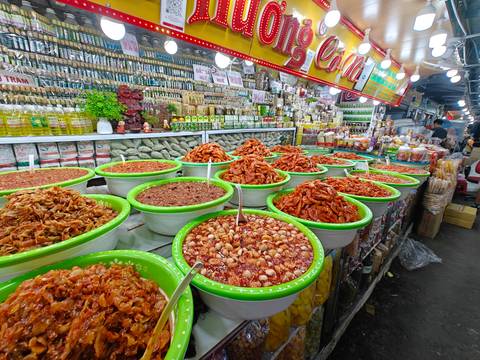 A bustling street market with a variety of food items in large bowls.