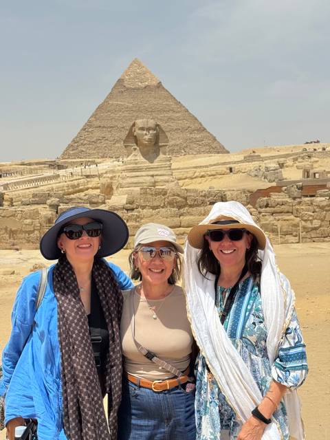 Three women posing in front of the Sphinx and pyramids.