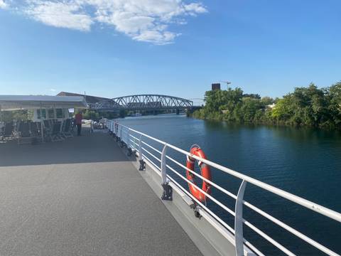 View from a boat deck with bridge crossing over a river.