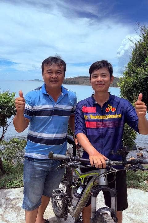       Two men posing for a picture with a scenic ocean backdrop.
  
