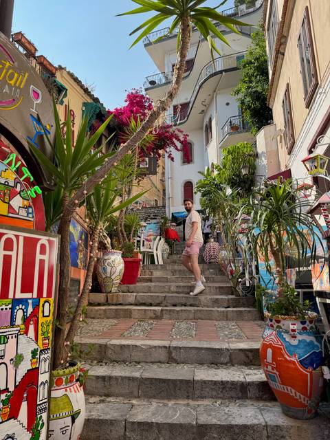 Person walking up colorful steps in a vibrant, decorated alley.