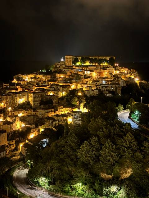 Illuminated town at night from a high vantage point.