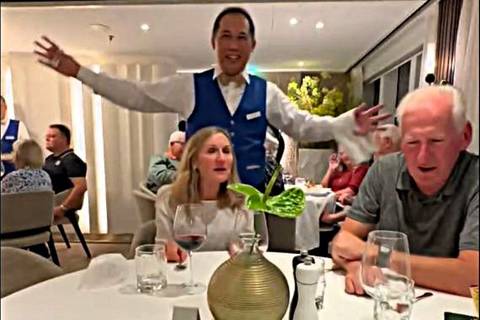 People dining in a restaurant, with a waiter in the background.