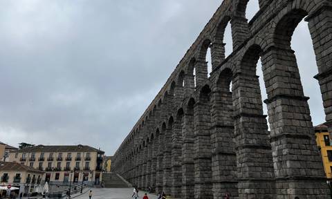 An ancient aqueduct in a cloudy urban setting.