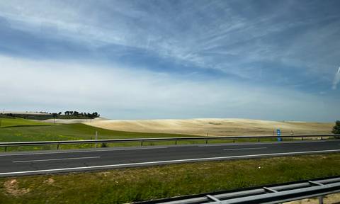 A highway cutting through open fields under a partly cloudy sky.