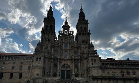 Silhouette of a grand historic cathedral against a dramatic cloudy sky.
