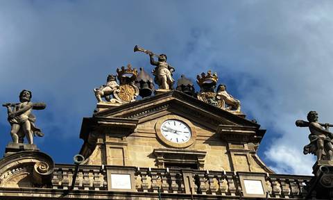 Ornate clock tower with statues against a blue sky.