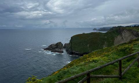 Rocky coastline with steep cliffs and ocean waves.