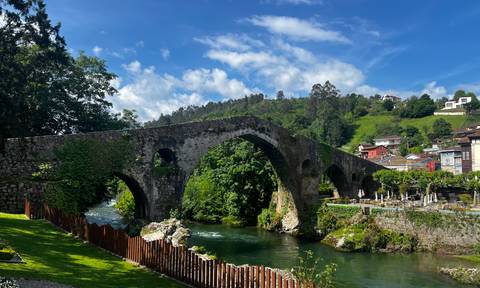 An ancient stone bridge over a lush river valley.