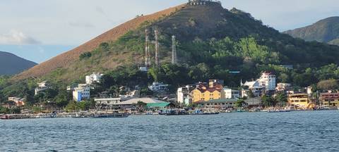       Coastal town with colorful buildings and a hill view.
  