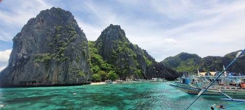       Boats sailing through clear waters surrounded by cliffs.
  