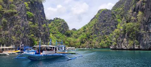       Boat navigating through a scenic bay with rocky cliffs.
  
